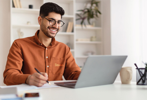 young Arab man smiling working at laptop