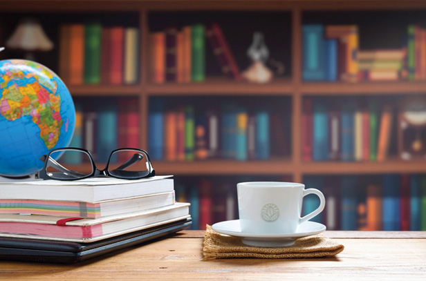 Globe, coffee, library of books in background